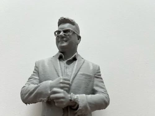 3D printed figure of a man in a suit, sculpted from customer photos and shown unpainted in gray